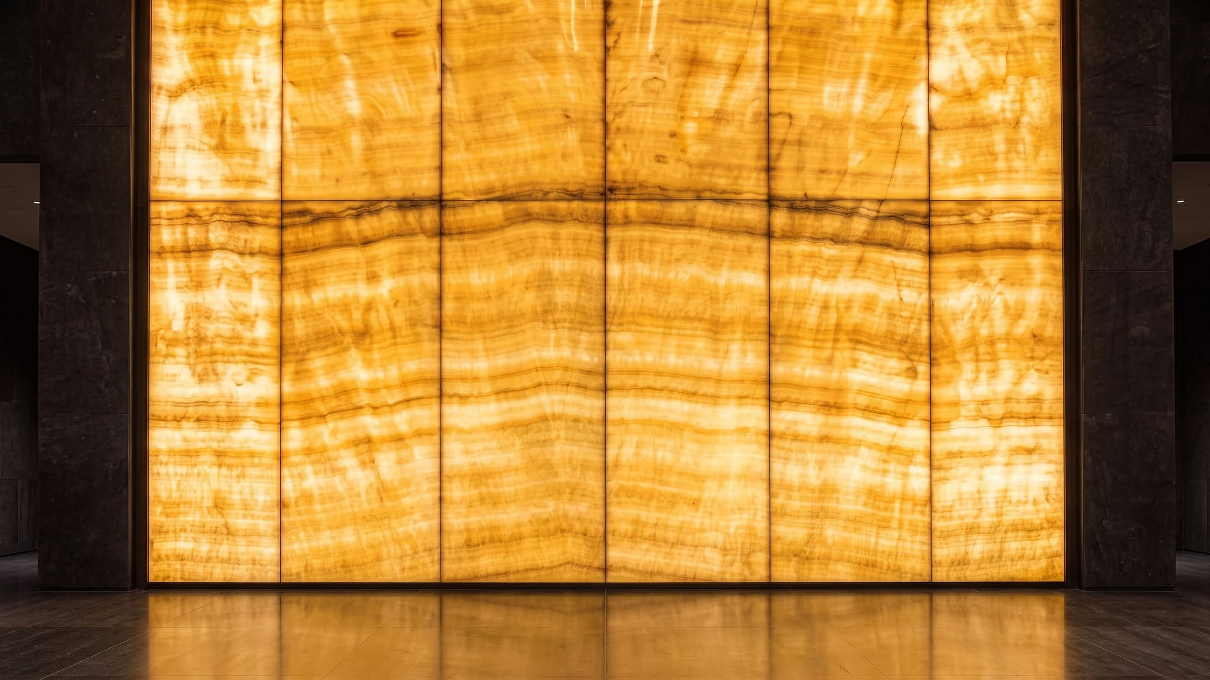 A full-height wall of backlit onyx, its banding glowing warm from within